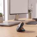 Black ergonomic vertical mouse on desk beside keyboard